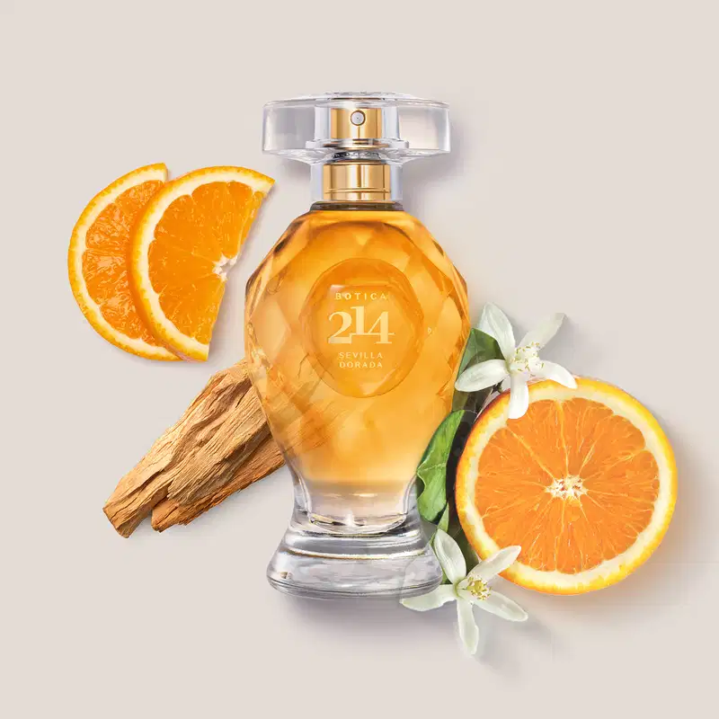 Frasco de Eau de Parfum Floral Frutal Botica 214 Sevilla Dorada em ambiente com laranjas fatiadas, flores brancas e pedaços de canela, sobre superfície clara.
