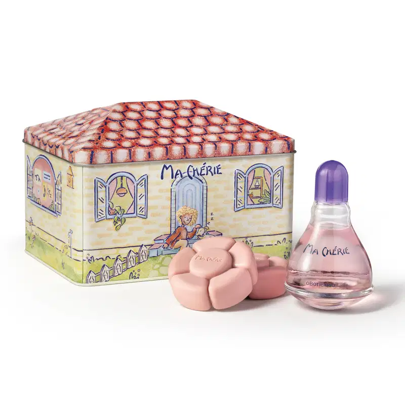 Conjunto de produtos Ma Chérie incluindo uma lata decorativa ilustrada com uma casa. Ao lado, o desodorante colônia Ma Chérie com líquido rosa e tampa roxa e sabonetes em formato de flor na cor rosa claro.