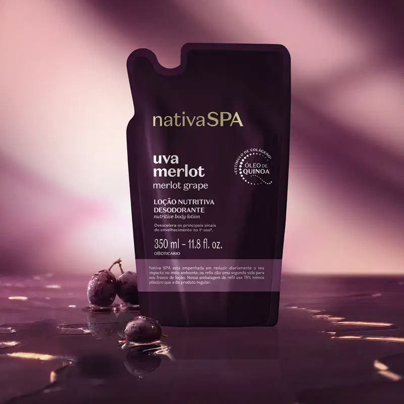 Embalagem roxa de loção hidratante corporal da marca Nativa SPA Uva Merlot, sobre superfície escura com reflexos e uvas frescas ao redor, em ambiente com iluminação rosada.