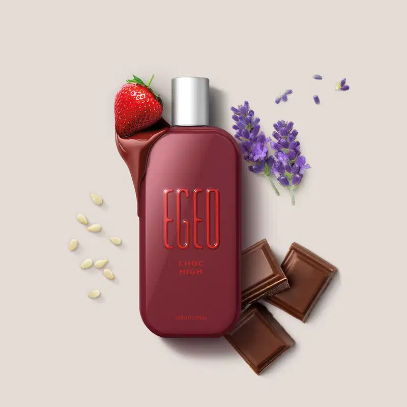 Frasco vermelho de desodorante colônia Egeo Choc High cercado por morangos, lavanda e barras de chocolate ao redor, sobre superfície clara.