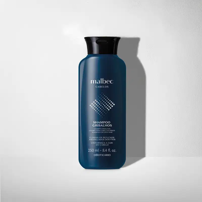 Frasco azul-marinho de shampoo da marca Malbec Cabelos para cabelos grisalhos, com rótulo branco contendo informações sobre o produto em fundo cinza com sombra.