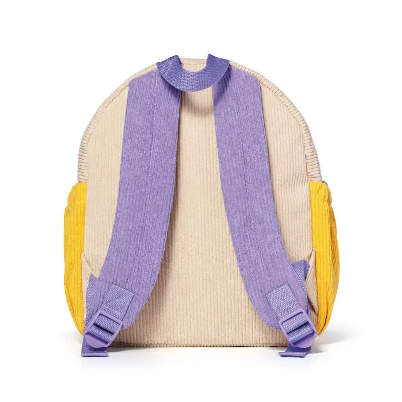Mochila infantil de veludo canelado nas cores bege, alça lilás e bolsos laterais amarelos, com zíper vista de costas.