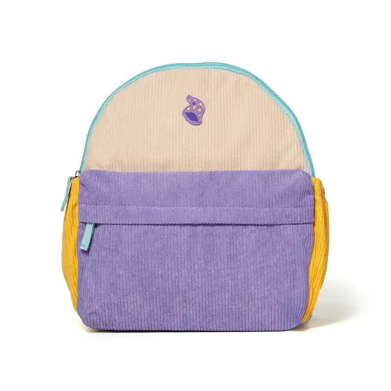 Mochila infantil de veludo canelado nas cores bege, lilás e amarelo, com zíper e aplicação de ícone em formato de touca de mago na parte frontal. Vista de frente.