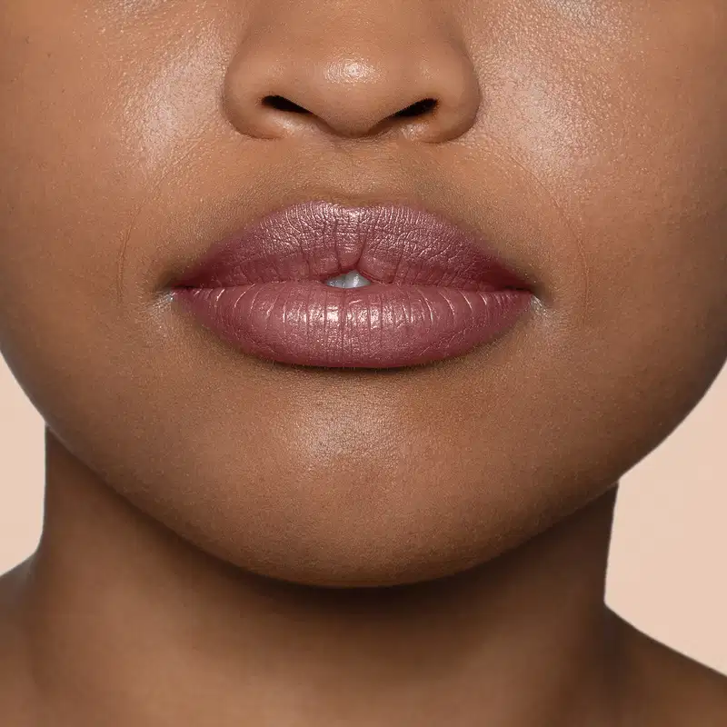 Close-up de um rosto feminino de pele negra evidenciando os lábios que usam o batom hidratante da marca Quem Disse, Berenice?.