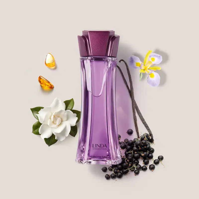 Vidro longo e transparente com líquido lilás, tampa roxa em formato de flor e letras roxas de desodorante colônia Linda Irresistível rodeado por camélia branca, âmbar e favas e flor de baunilha.