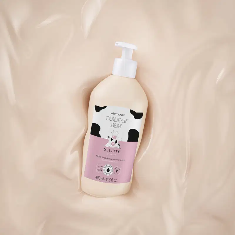 Embalagem branca com rótulo rosa, branco e ilustração de vaca de loção hidratante corporal da marca Cuide-se bem Deleite sobre superfície clara e suave.