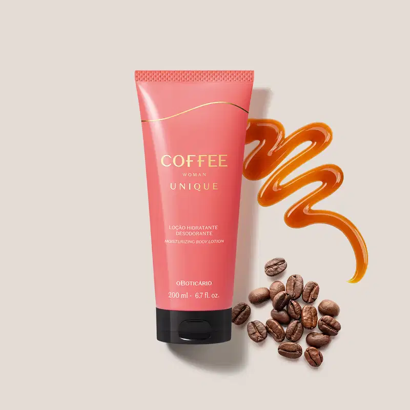 Imagem de bisnaga de loção hidratante desodorante corporal da linha Coffee Woman Unique, em embalagem rosa com tampa preta e detalhes dourados cercada por grãos de café e um fio de caramelo formando um caminho sinuoso sobre superfície clara.