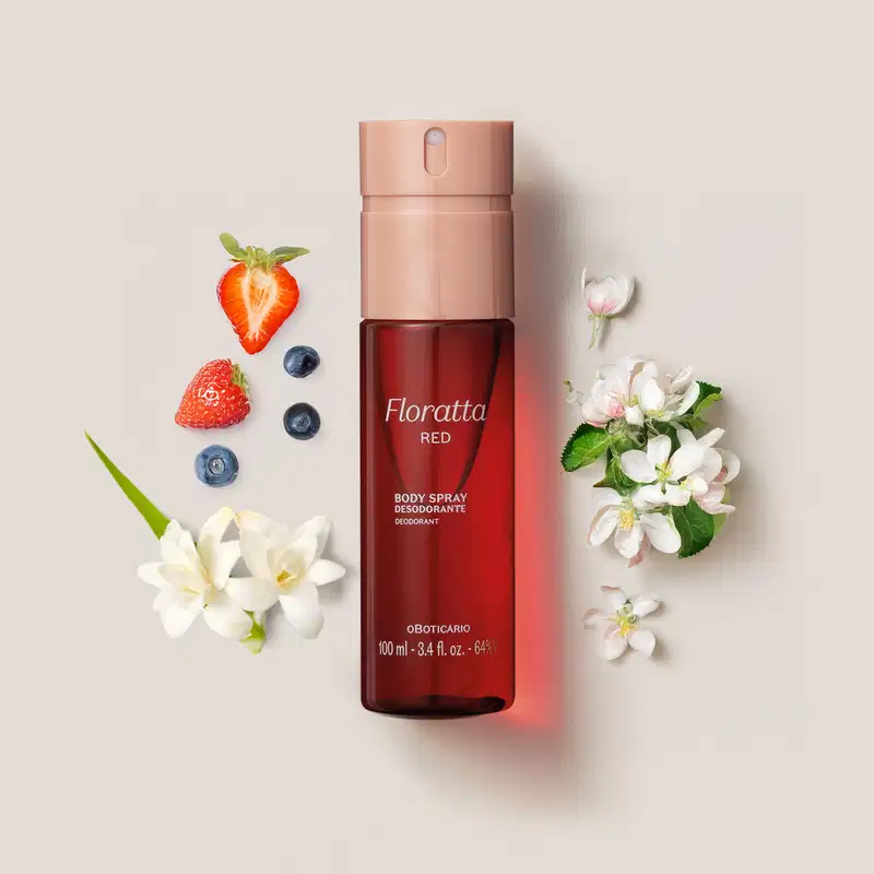 Frasco cilíndrico de body spray na cor vermelha com tampa borrifadora rosa da marca Floratta Red cercado por flores brancas de baunilha e frutas vermelhas, como morangos e mirtilos.