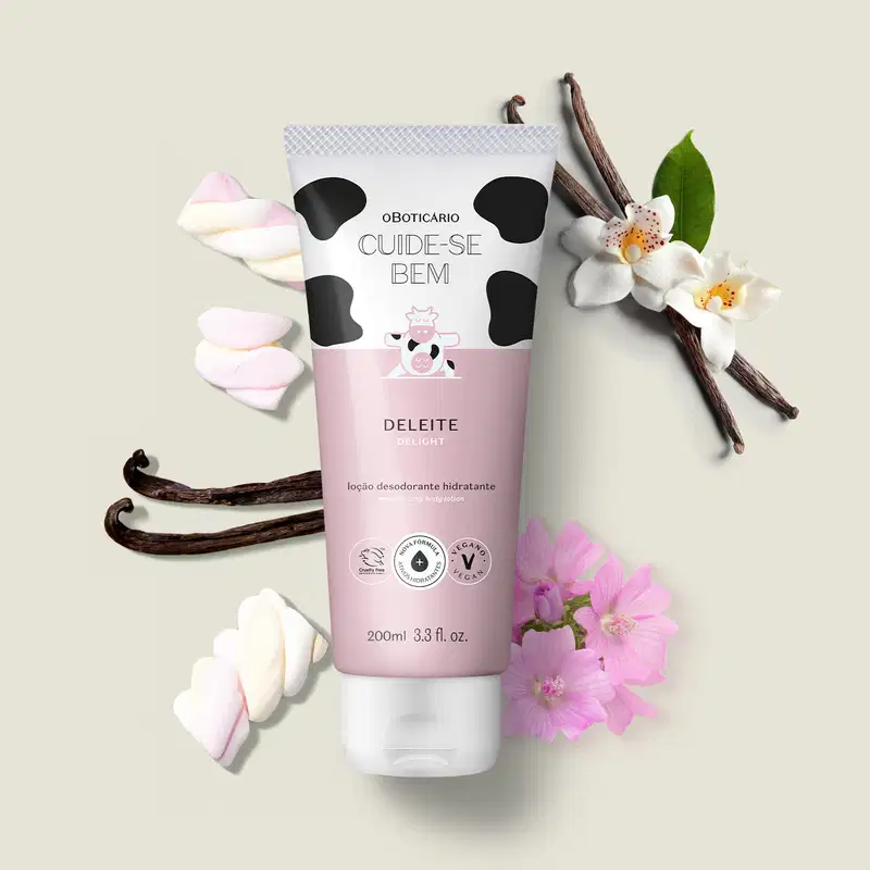 Tubo de loção desodorante hidratante da marca Cuide-se bem Deleite cercada por flores brancas e rosas, favas de baunilha e tranças de marshmallow em superfície clara, compondo cenário natural e delicado.