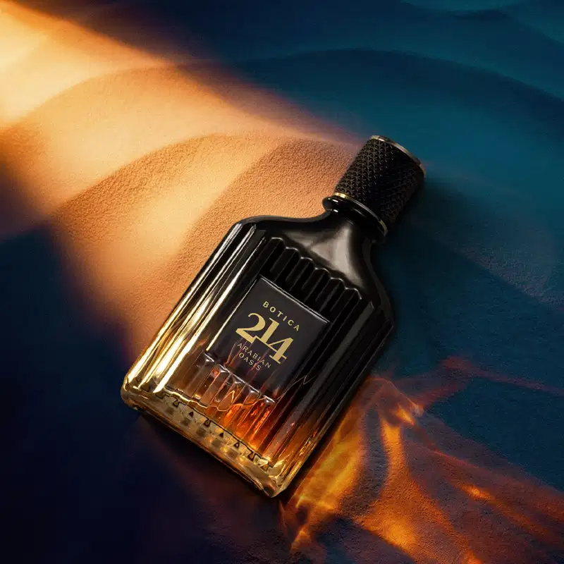 Embalagem de perfume Botica 214 em ambiente com iluminação dramática, com tons quentes e azuis, sugerindo um cenário elegante e sofisticado para o uso deste produto de beleza.