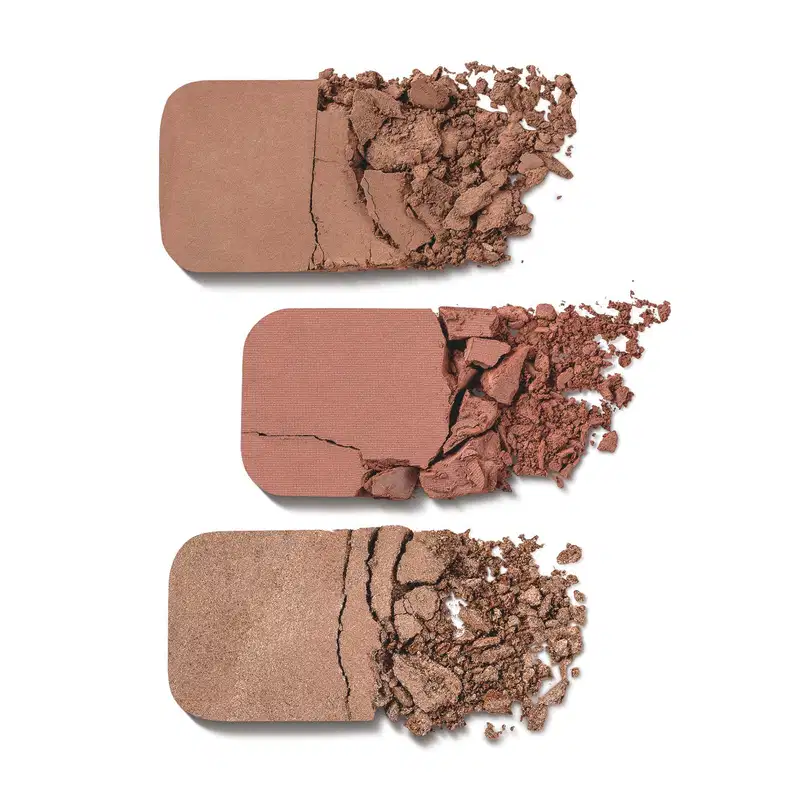 Imagem de três amostras de sombra compacta em tons de marrom, com diferentes texturas e acabamentos, dispostas sobre fundo branco.