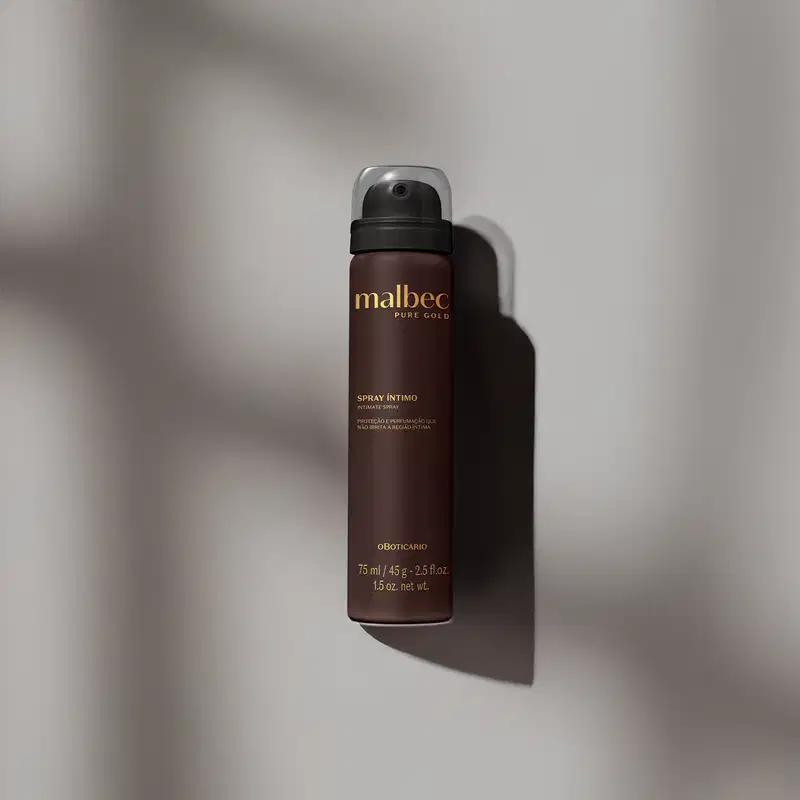 Imagem de um frasco de spray íntimo da marca Malbec Pure Gold em fundo cinza, com sombras projetadas, em ambiente minimalista e monocromático.