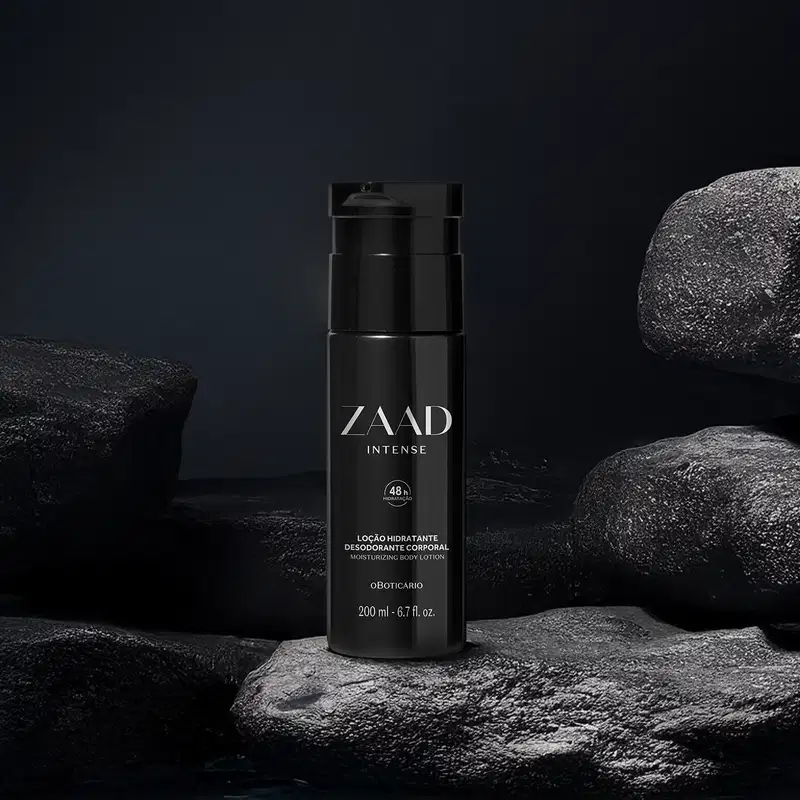 Imagem de um frasco preto de loção hidratante corporal da marca Zaad Intense sobre superfície rochosa escura, com pedras ao redor em cenário sombrio e monocromático.