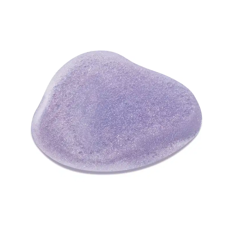Objeto de textura suave e brilhante com tons de lavanda. Superfície irregular e granulada, com aspecto cristalino. Item de perfumaria com aparência delicada e refinada.