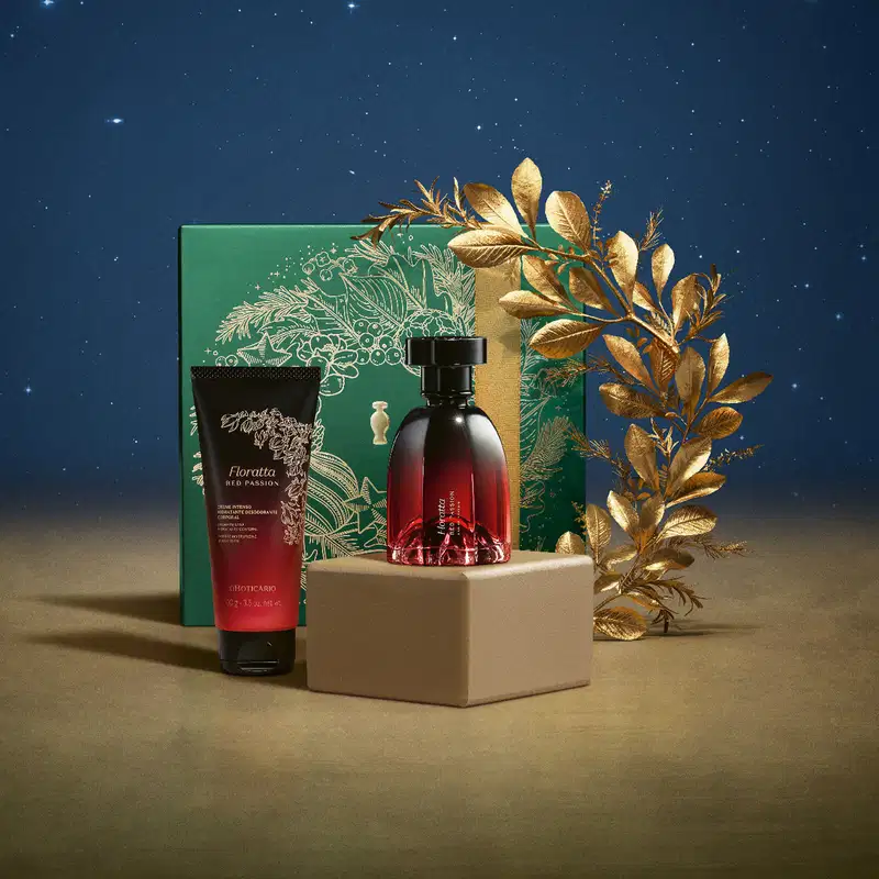 Imagem do Kit Presente Natal Foratta Red Passion com um vidro vinho e preto de desodorante colônia, frasco na mesma cor de creme hidratante corporal e uma caixa verde presenteável com estampa natalina em cenário com fundo azul-escuro e superfície marrom.