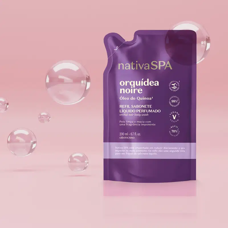 Imagem de embalagem refil roxa da marca Nativa SPA Orquídea Noire com sabonete líquido, cercada por bolhas de sabão em fundo rosa.