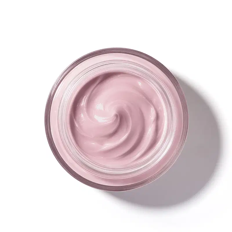 Pote de vidro visto de cima com foco na textura do creme com padrão de espiral suave de textura cremosa e brilhante em tom de rosa claro.