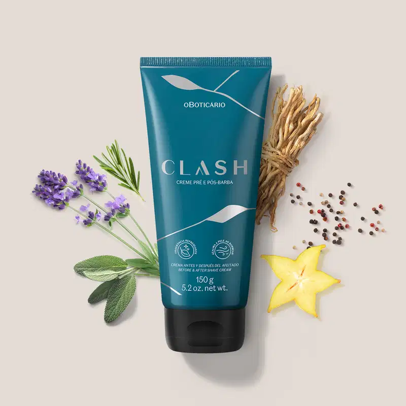 Tubo de creme pré e pós-barba da marca Clash, em embalagem azul-esverdeada, rodeado por flores de lavanda, galhos de alecrim, especiarias e uma fatia de carambola amarela, sobre uma superfície clara.