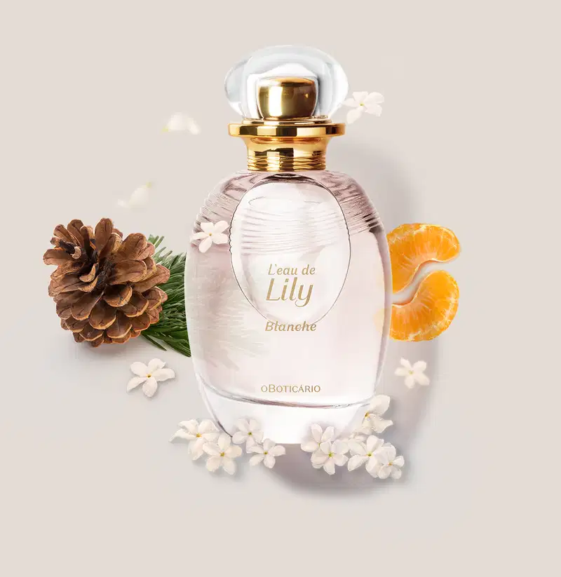 Frasco de desodorante colônia da marca L'eau de Lily Blanche em ambiente com flores brancas, pinhas e fatias de laranja, sobre superfície clara.