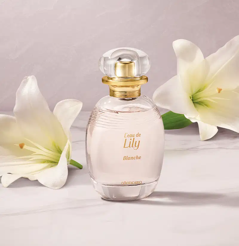 Frasco de desodorante colônia L'eau de Lily Blanche sobre superfície clara, com flores brancas ao redor, em ambiente iluminado e minimalista.
