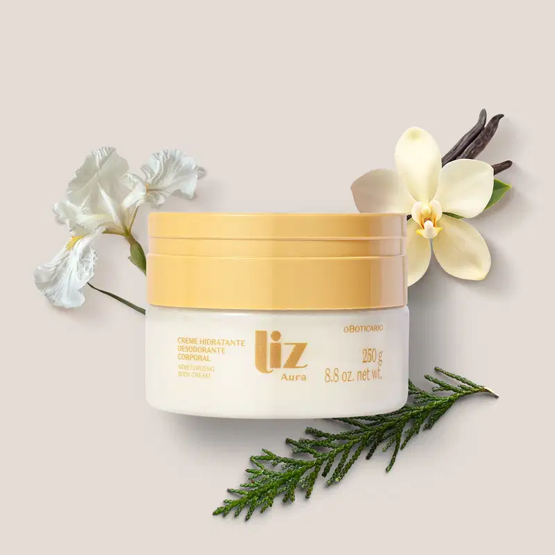 Recipiente de creme hidratante corporal da marca Liz Aura, com tampa e rótulo em letras douradas em ambiente com flores brancas e verdes em um fundo bege claro.