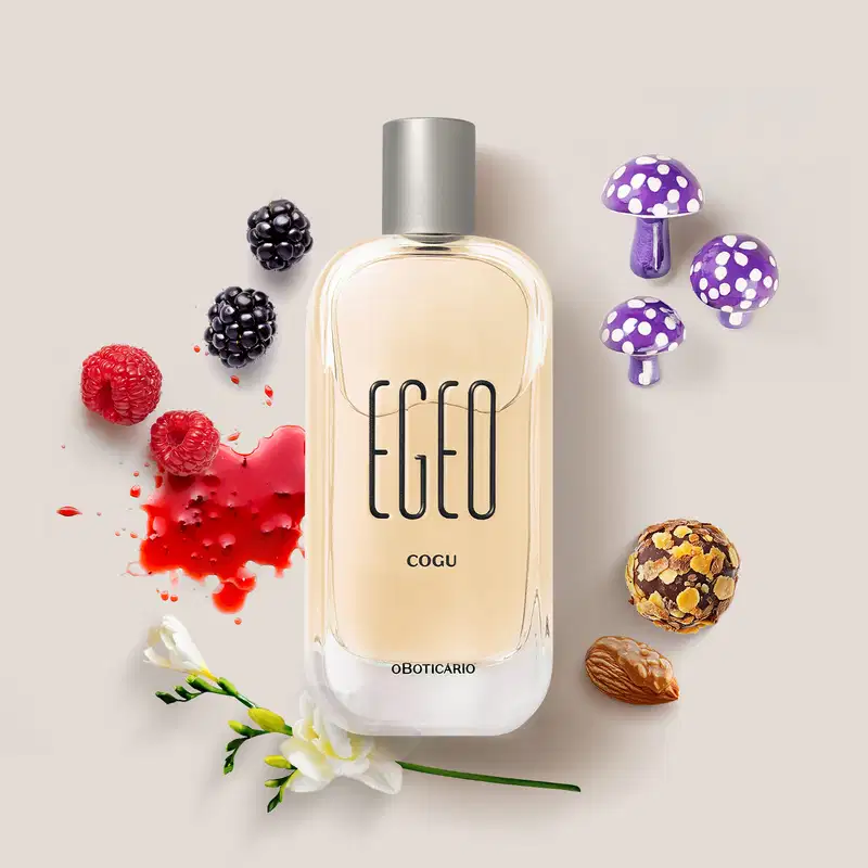 O frasco é de vidro transparente, com um design elegante e simples. Ao redor do frasco, há alguns elementos decorativos, como flores, cogumelos estilizados e frutas vermelhas, que parecem complementar a apresentação do produto.
