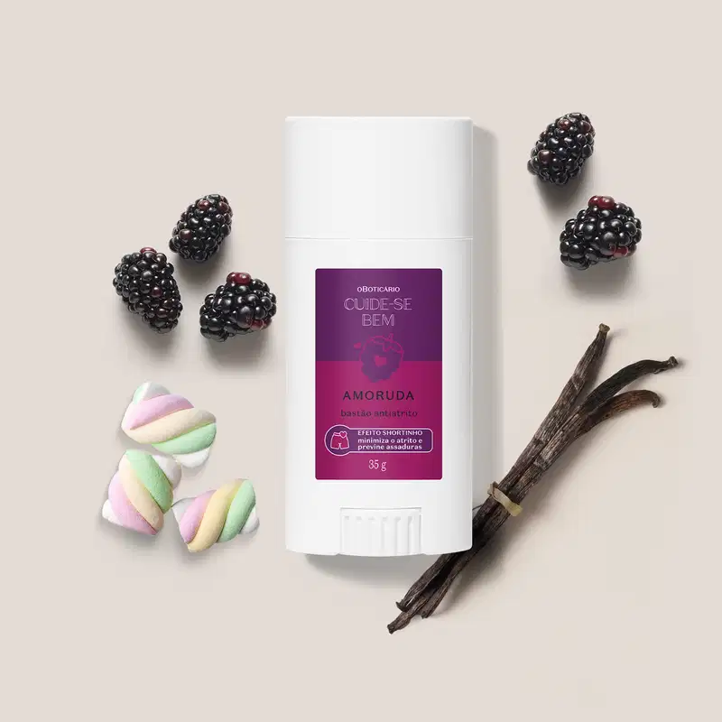 Embalagem branca de bastão anti-atrito da marca Cuide-se bem Amoruda, rodeada por amoras frescas, marshmallows coloridos e bastões de baunilha em superfície bege clara.