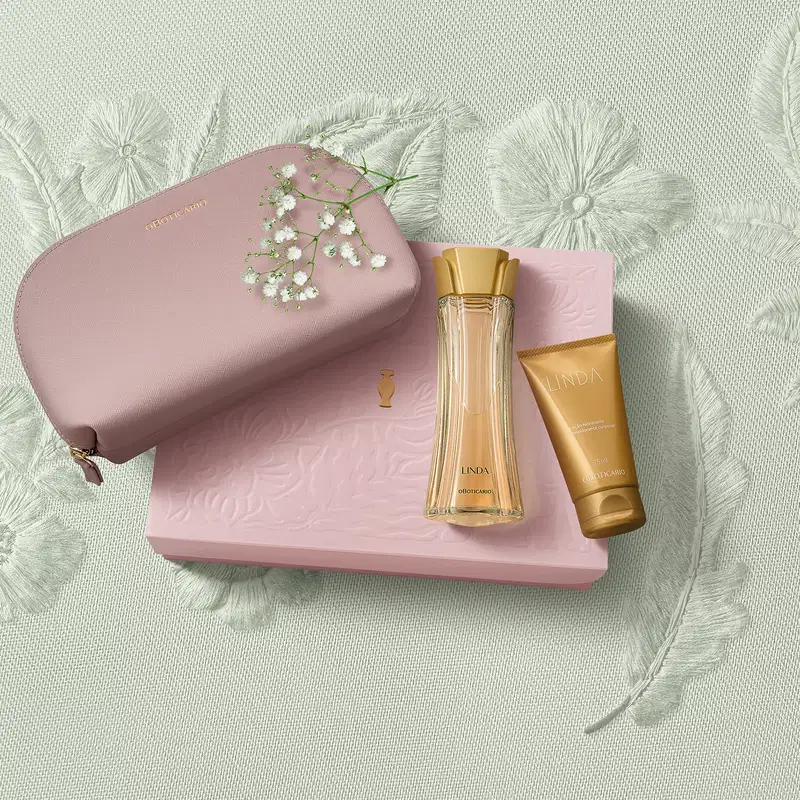 Caixa rosa com floral em relevo, nécessaire rosa e dois produtos da marca Linda: frasco de creme hidratante corporal na cor laranja e vidro curvilíneo com líquido alaranjado e tampa laranja de desodorante colônia em fundo bege floral.