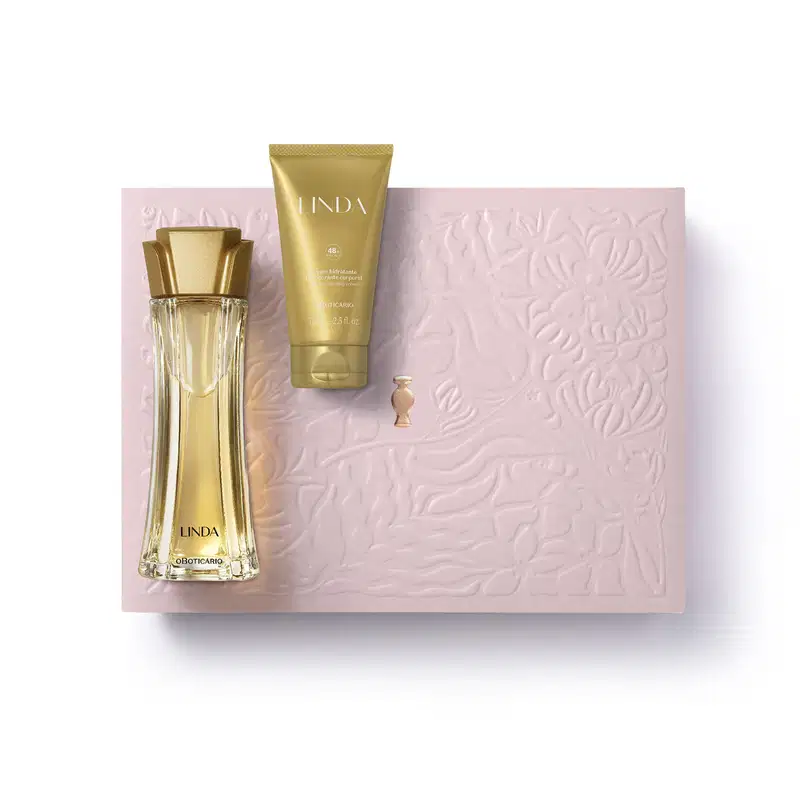 Caixa rosa com floral em relevo, nécessaire rosa e dois produtos da marca Linda: frasco de creme hidratante corporal na cor laranja e vidro curvilíneo com líquido alaranjado e tampa laranja de desodorante colônia.