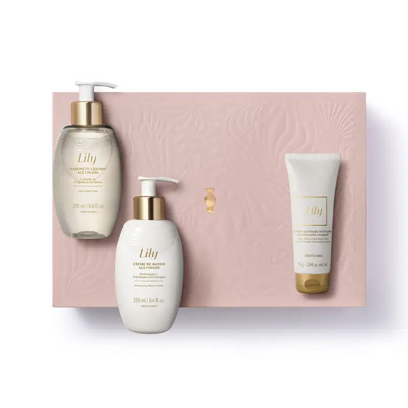 Caixa rosa com detalhe dourado e três produtos de cuidados corporais da marca Lily: bisnaga de creme acetinado corporal, frasco de creme de banho acetinado e outro frasco de sabonete líquido, todos em tons de dourado e branco.