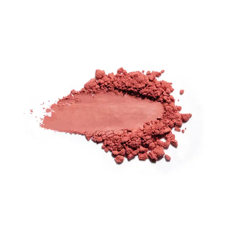 Textura de pó rosa-avermelhado com acabamento acetinado e superfície irregular, espalhada sobre fundo branco.