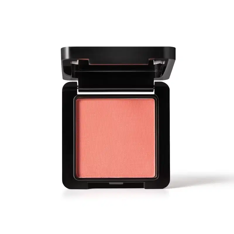 Embalagem preta de blush compacto da marca Make B. aberta, com formato quadrado, e dentro, vemos o produto de tonalidade coral vibrante.