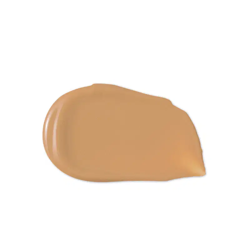 O produto de beleza apresenta uma textura cremosa e uniforme, com uma coloração bege suave e brilho sutil, sugerindo uma consistência macia e aveludada.
