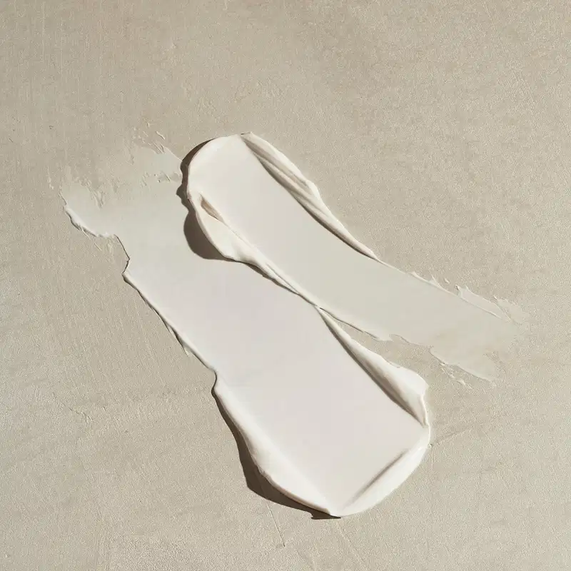 Imagem da textura branca e cremosa de creme hidratante para as mãos Nativa spa Quinoa, com superfície lisa e brilho suave, sobre fundo neutro.