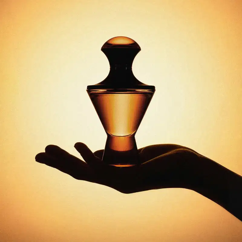 Imagem de uma mão segurando um vidro elegante e sofisticado de Eau de Parfum da marca Hadiya em fundo marrom iluminado. Seu formato transmite luxo e exclusividade. mostrando se tratar de uma fragrância cheia de personalidade.