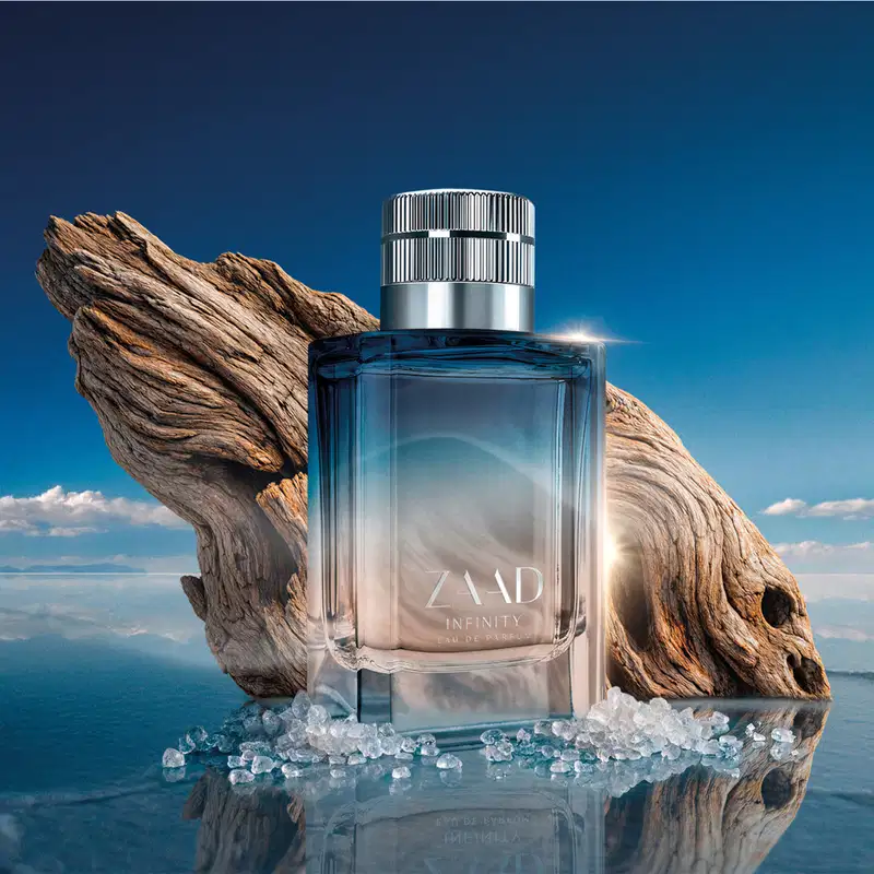 Frasco de item de perfumaria Zaad Infinity em cenário natural com madeira, sal e céu azul, refletido em superfície espelhada.
