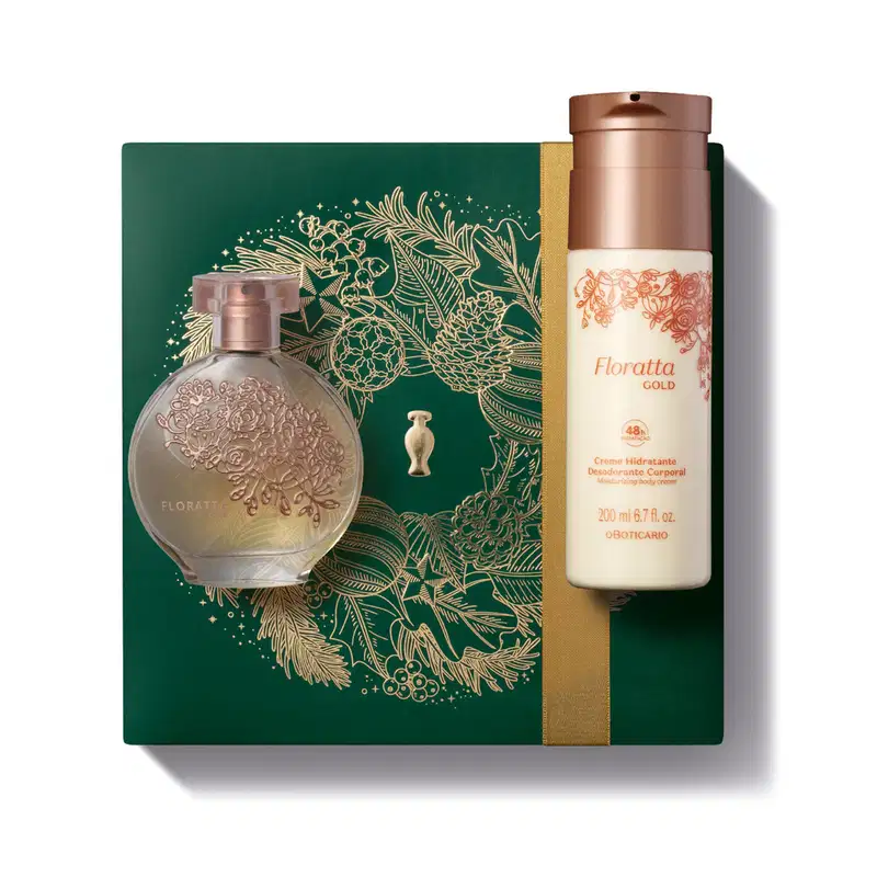 Frasco de vidro de desodorante colônia Floratta Gold arredondado e transparente, com flores douradas gravadas em relevo e frasco branco com tampa dourada de body splash da mesma linha sobre uma caixa presenteável verde com ilustração natalina.