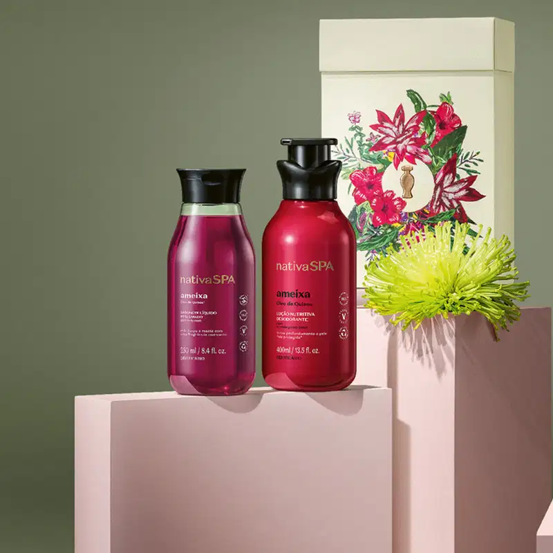 Imagem de kit de presente Nativa SPA Ameixa contendo  um frasco de sabonete líquido, outro de loção desodorante corporal e uma caixa branca com ilustração floral. O kit está sobre quadrados brancos com fundo cinza.