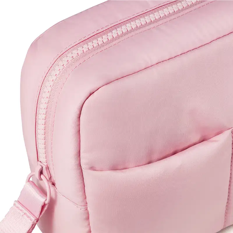 Imagem de uma nécessaire rosa clara com puxador. A bolsa tem vários compartimentos e um zíper na parte frontal. Não há nenhum texto ou rótulo visível na imagem.
