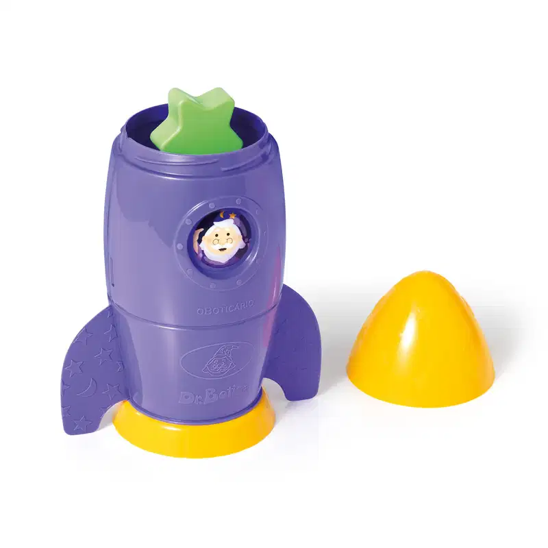 Foguete de brinquedo roxo com detalhes amarelos e estrelas, contendo um rosto sorridente em seu centro, posicionado sobre uma superfície amarela.