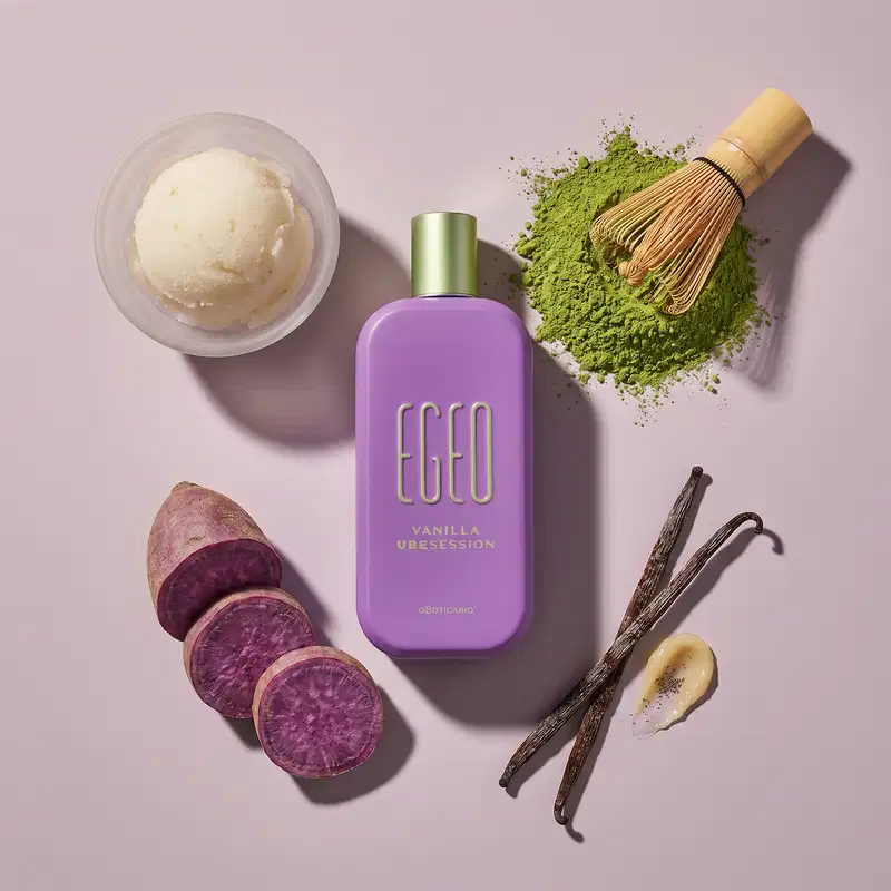 Recipiente de item de perfumaria da marca Egeo em tom lilás, com ingredientes naturais como baunilha, batata-doce roxa e matcha sobre superfície rosa.