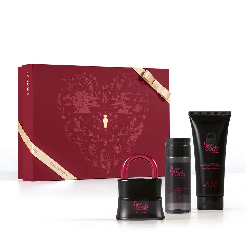 Caixa vermelha com detalhes dourados e fita dourada fina. A frente dela, três itens de perfumaria da marca Her Code Climax, sendo um desodorante colônia preto com tampa em formato de cadeado, um body spray preto e uma bisnaga preta de loção corporal.