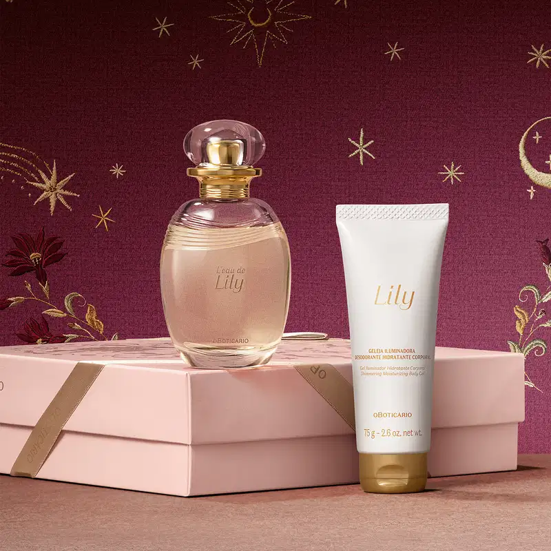 Embalagem rosa posicionada horizontalmente sobre superfície rosa com frasco de item de perfumaria da marca L'Eau de Lily sobre ela e bisnaga de creme corporal branca ao lado, sobre fundo bordô com estrelas douradas.