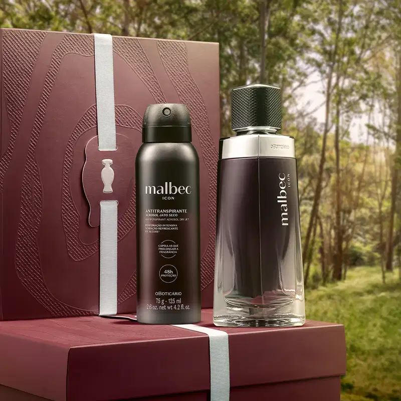 Caixa e embalagem de item de perfumaria da marca Malbec em primeiro plano, com fundo de floresta verde e árvores ao redor.