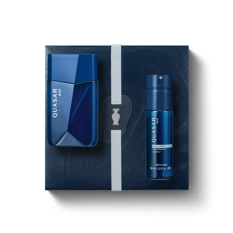 kit de item de perfumaria Quasar composto por frasco de fragrância azul e embalagem de papelão azul-marinho com textura ondulada e fita branca.