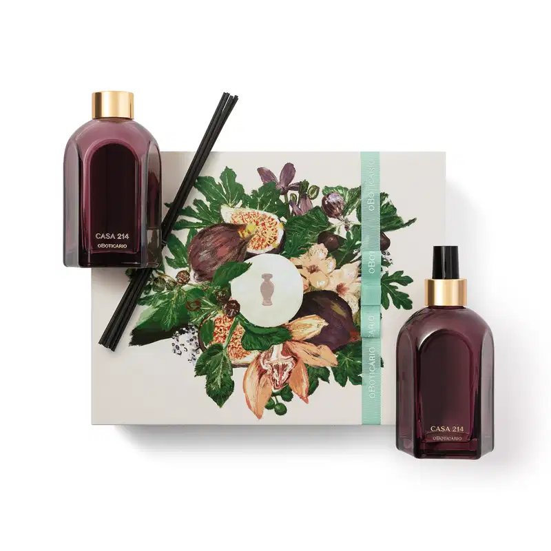 No canto superior esquerdo está um vidro de difusor com varetas pretas, ao centro está uma caixa com faixa verde e flores ilustradas e no canto inferior direito está um vidro de aromatizador de ambientes. As embalagens são roxas, retangulares e elegantes.