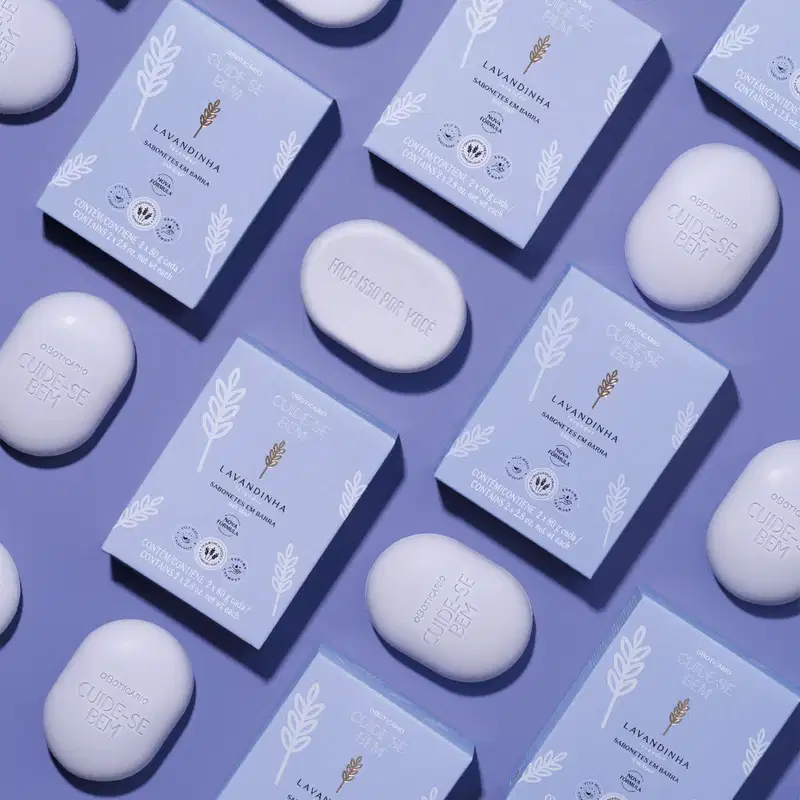 Caixas e sabonetes brancos com rótulos da marca Lavandinha, contendo informações sobre o produto e selos de certificação.