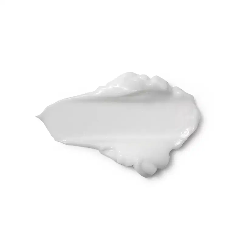 Textura branca e cremosa de produto de corpo e banho, com aspecto liso e brilhante, espalhada sobre superficie clara, ocupando grande parte da imagem.