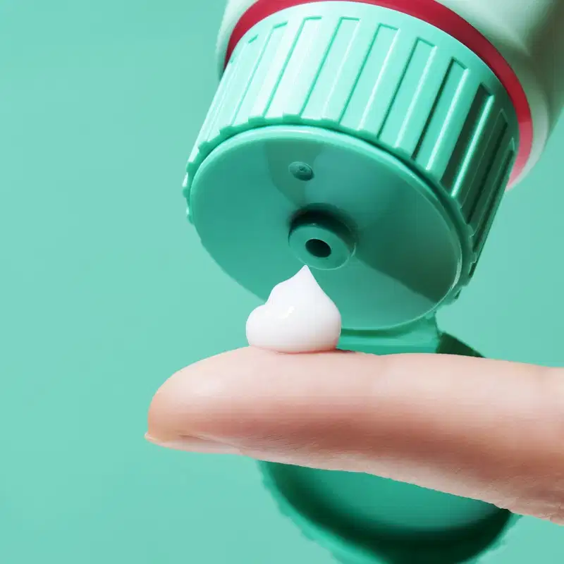 O produto de beleza apresenta uma textura cremosa e suave, com uma coloração verde clara e brilhante. Sua consistência parece ser leve e macia, com uma aparência uniforme e agradável.