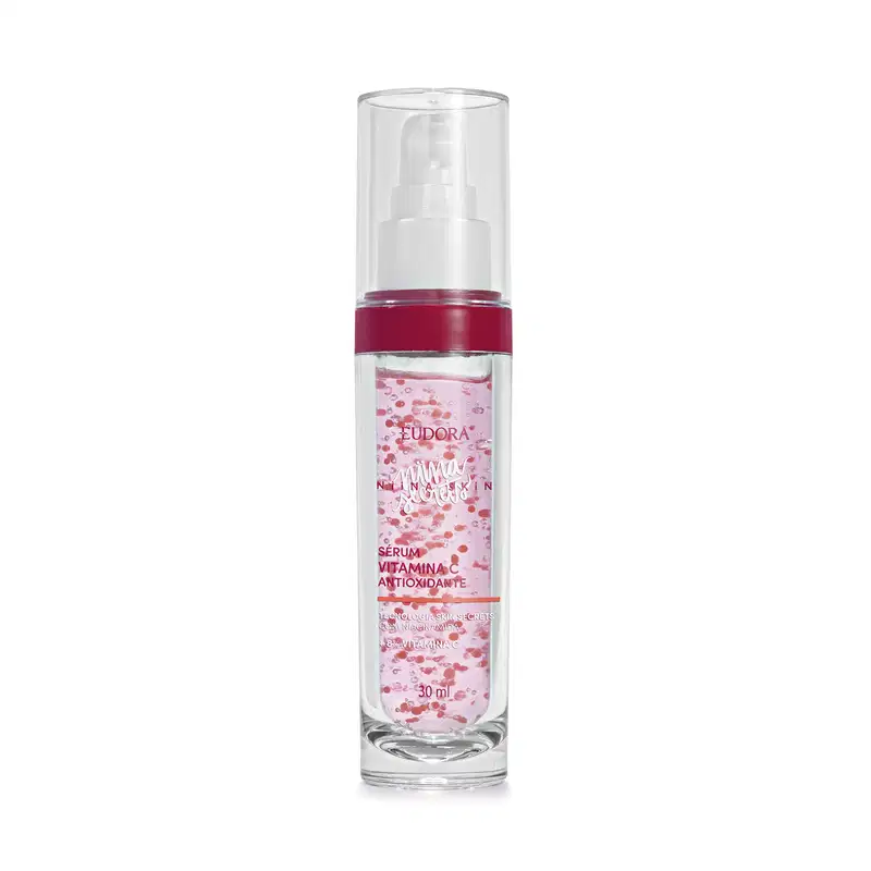 Frasco cilíndrico de vidro transparente com tampa branca tipo pump e tampa protetora. Produto rosa claro contendo pequenos pontos vermelhos. Rótulo transparente em em letras brancas e rosa pink.